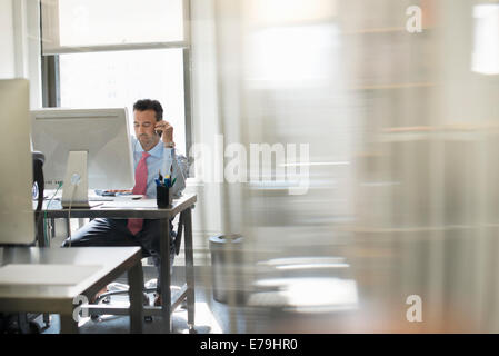 A man seated at a computer screen working on his own. Stock Photo