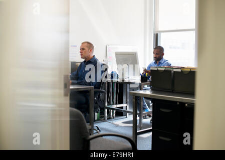Two men working in an office, using computers. Stock Photo