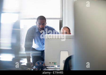 Two men working in an office, both looking at a computer monitor. Stock Photo