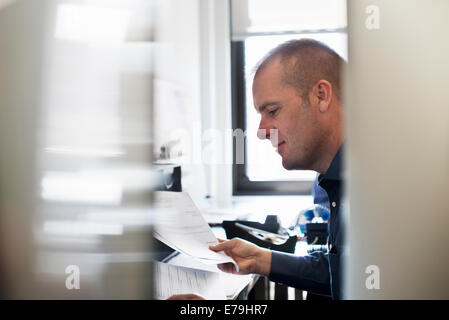 A man working in an office, reading paperwork. Stock Photo