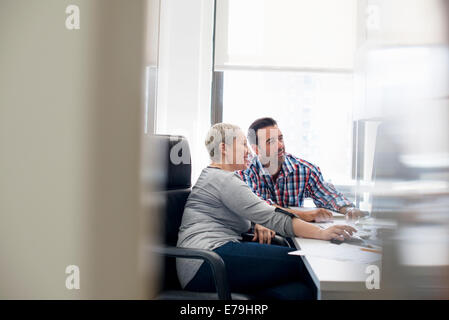 Two people, colleagues in an office looking at a computer screen. Stock Photo