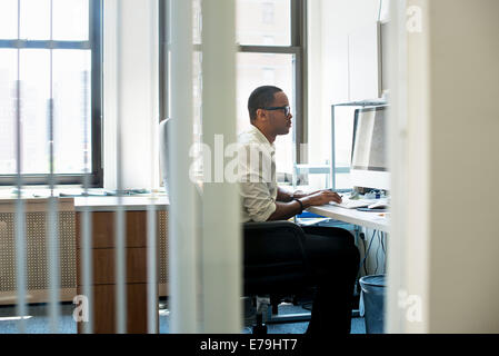 A man working in an office seated at a desk. Looking at a computer screen. Stock Photo