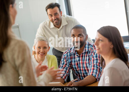 Five people in an office, two men and three women talking. Stock Photo