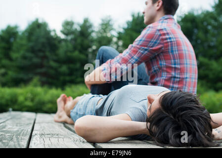 A couple relaxing on a jetty overlooking a mountain lake.