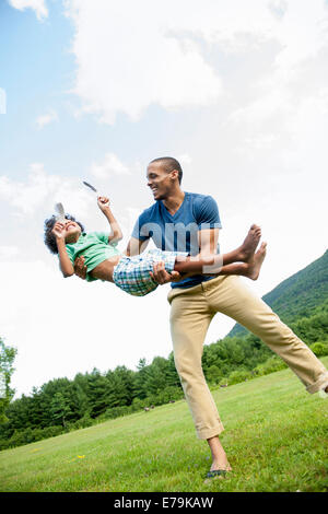 A man lifting his son up in his arms, playing outdoors. Stock Photo