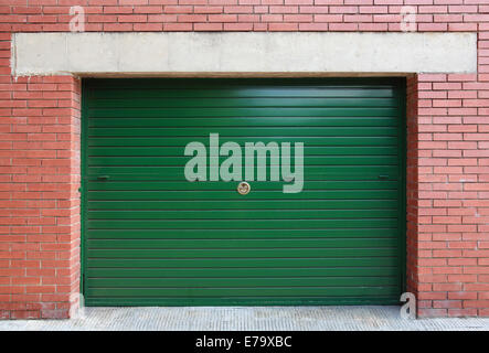 Green metal garage gate in red brick wall, background texture Stock Photo