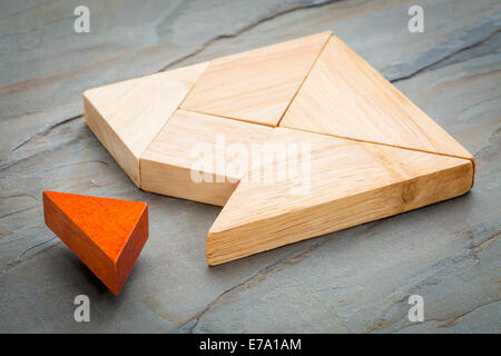 a missing piece in a square built from tangram shapes, a traditional Chinese puzzle game, slate rock background Stock Photo