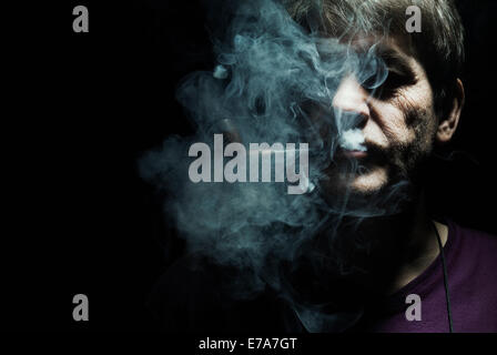 A serious man smoking a pipe, staring ominously into the camera Stock Photo