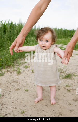 Father helping baby girl to walk Stock Photo