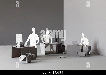 Paper businessmen working at desks in office Stock Photo
