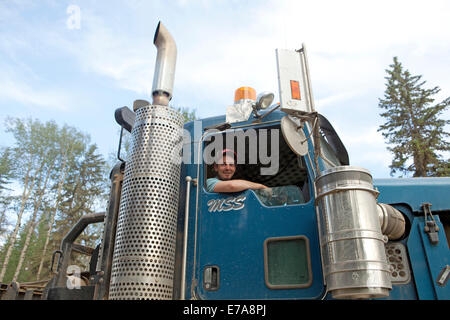 Portrait of haulage truck driver looking out of driver cab window, low angle view, Canada Stock Photo