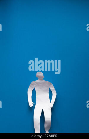 Directly above shot of crumpled paper man relaxing on blue background Stock Photo