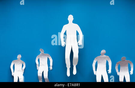 Paper businessman flying while colleagues standing down representing leadership over blue background Stock Photo