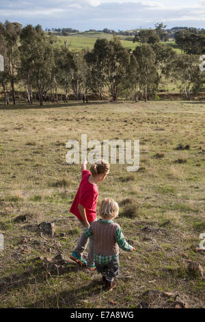 A girl holding hands with a young boy and walking in nature Stock Photo