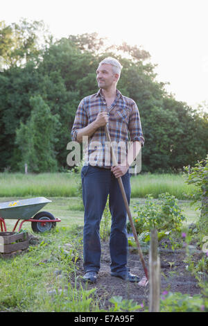 Mature man looking away while working in vegetable garden Stock Photo