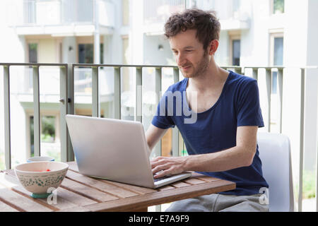 Young man using laptop at porch Stock Photo