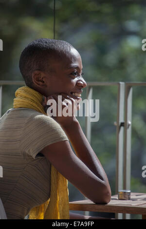 Side view of smiling young woman sitting at table on patio Stock Photo
