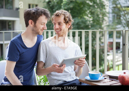 Young gay couple using digital tablet at porch Stock Photo