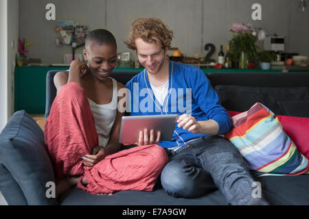Smiling friends using digital tablet together on sofa at home Stock Photo