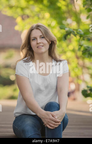 Portrait of smiling mid adult woman sitting in park Stock Photo