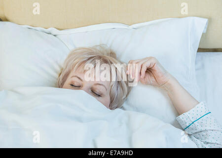 Mature woman sleeping in bed Stock Photo