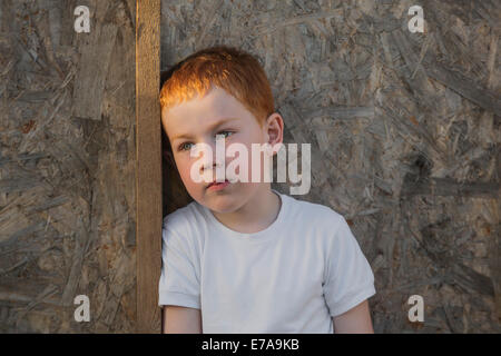 Thoughtful boy looking away against wall Stock Photo