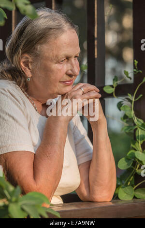 Thoughtful senior woman standing in balcony Stock Photo