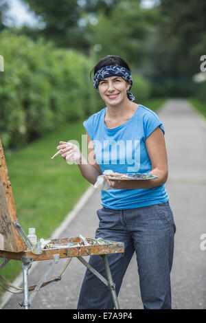 Portrait of happy female painter in park Stock Photo