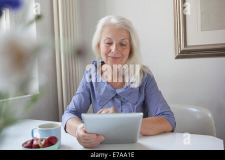 Senior woman using digital tablet at home Stock Photo