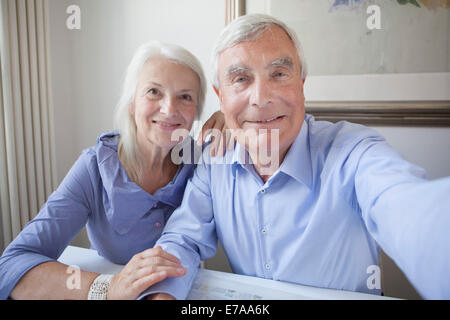 Portrait of smiling senior couple sitting together at table in house Stock Photo