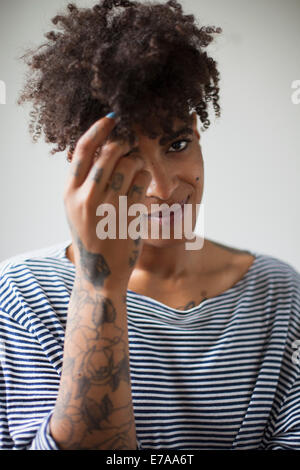 Portrait of smiling young woman playing with hair against gray background Stock Photo