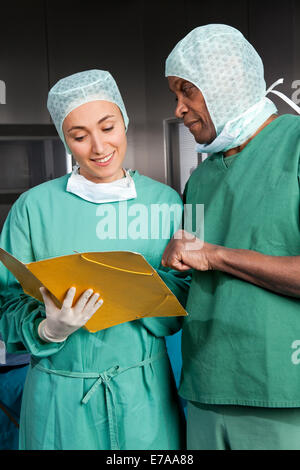 Two surgeons in scrubs consulting over a medical file Stock Photo