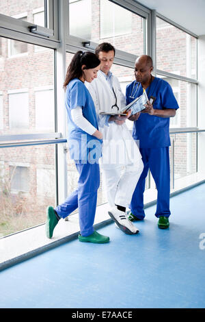 Three medical professionals consulting over a medical file in a hospital Stock Photo