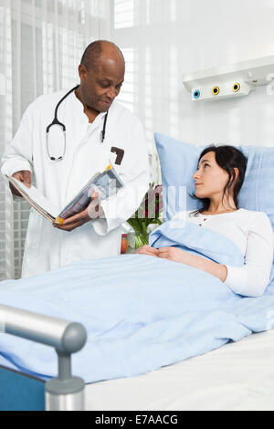 A doctor talking to a patient lying in a hospital bed Stock Photo