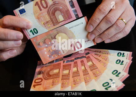 An employee of the German Federal Bank holds new 10 euro banknotes during a press conference in Frankfurt Main, Germany, 11 September 2014. The new banknote with new security features, different design and dirt-resistant coating will go into circulation on 23 September. Photo: ARNE DEDERT/dpa Stock Photo