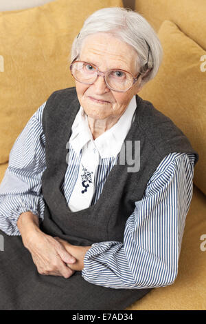 Portrait of a senior woman looking at the camera while sitting on sofa Stock Photo