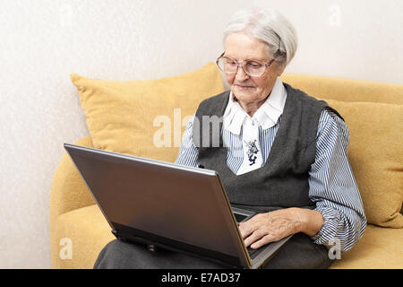 Senior woman using laptop computer while sitting on sofa Stock Photo