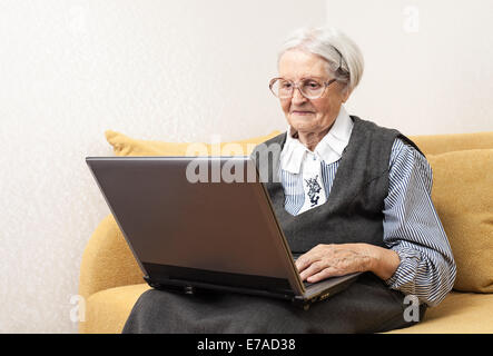 Senior woman using laptop computer while sitting on sofa Stock Photo