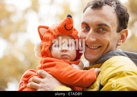 Young Caucasian man and his little son in fox costume in autumn park Stock Photo