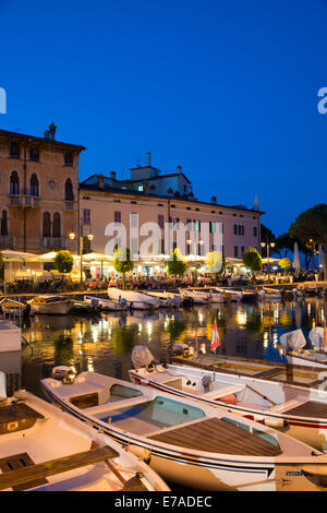 The restaurants of Desenzano del Garda cluster around the the pretty harbour and once the sun sets can become quite busy. Stock Photo