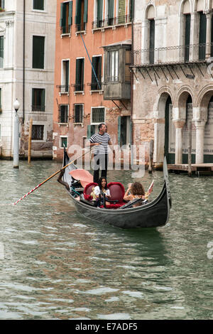 Two tourists enjoying their ride in a traditional Gondola along the Grand Canal in Venice Italy Stock Photo