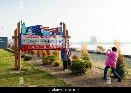 Asian tourists pose in front of the Welcome to the United States of America sign in Blaine Washington Stock Photo