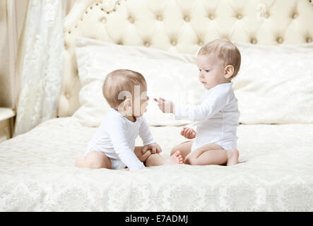 Two baby boys playing on bed at home Stock Photo