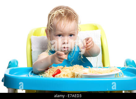 Little blond boy eating spaghetti, with pasta on his head Stock Photo