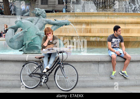 London, UK. Young woman with a bike looking at a map in Trafalgar Square Stock Photo