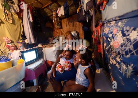 Woman with two children watching television in a shack, Camp Icare for earthquake refugees, Fort National, Port-au-Prince, Haiti Stock Photo