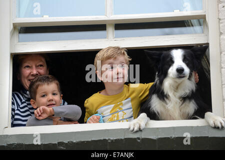 Family children with pet dog looking through home window Britain Uk Stock Photo