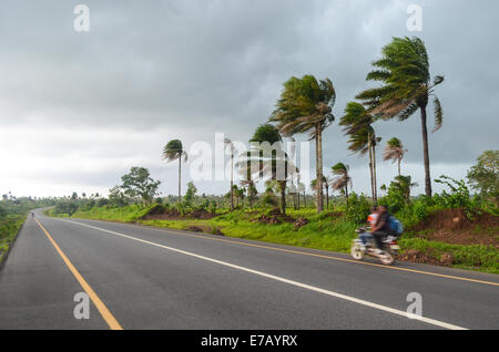 Motorbike speeding on the tar road just before a heavy rainfall during the rainy season in Sierra Leone, West Africa Stock Photo