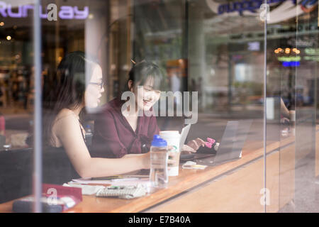 Two women seen through window of coffee store in Singapore Stock Photo