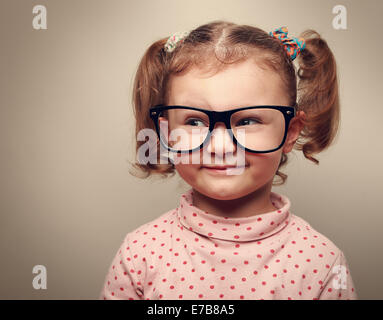 Funny kid girl in glasses looking on empty copy space and thinking. Instagram effect Stock Photo